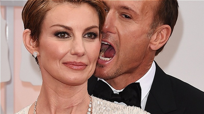 Faith Hill souriante aux cheveux courts, Tim McGraw faisant semblant de la mordre