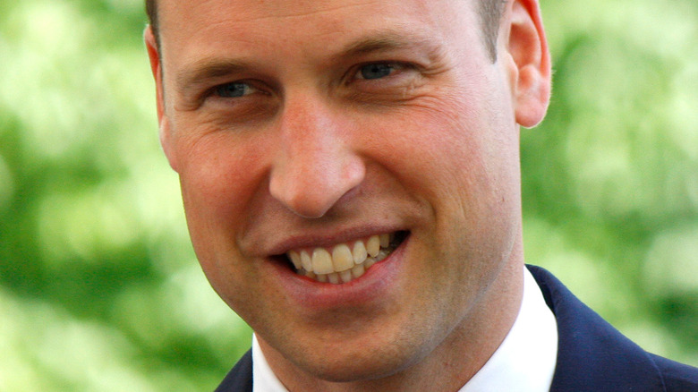 Le prince William sourit dans un costume bleu marine