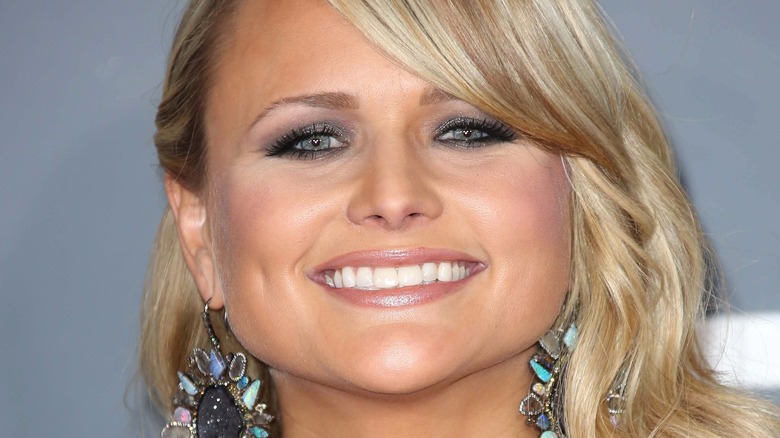 Miranda Lambert grand sourire portant d'énormes boucles d'oreilles