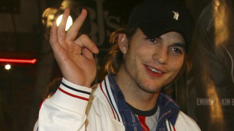 Ashton Kutcher rit avec la main en l'air