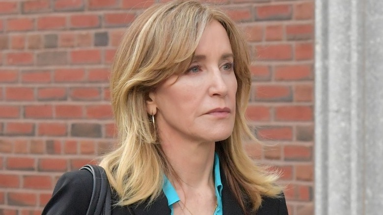 Felicity Huffman marchant devant un mur de briques