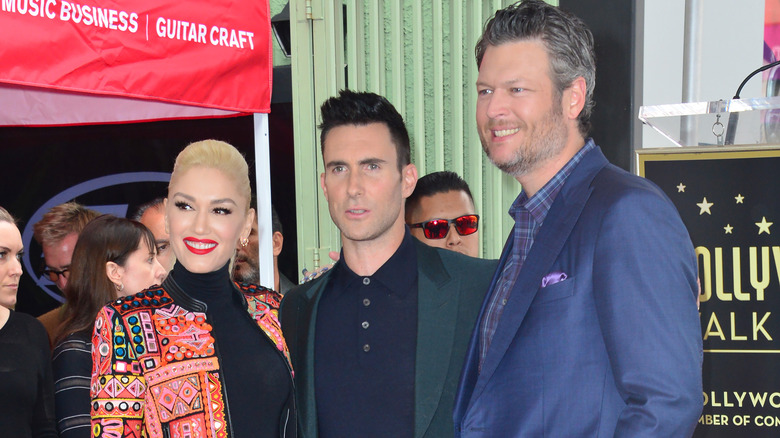 Gwen Stefani, Blake Shelton et Adam Levine sourient une photo de groupe