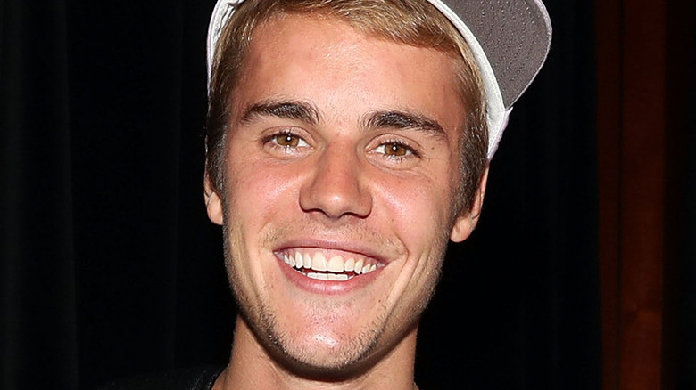 Justin Bieber souriant dans une casquette de baseball blanche