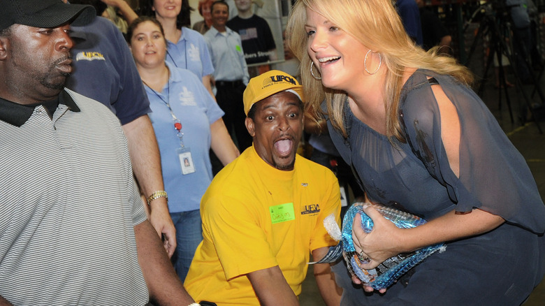 Trisha Yearwood attrape une dinde congelée en faisant du bénévolat avec Second Harvest Food Banks en 2010 avec Paula Deen.