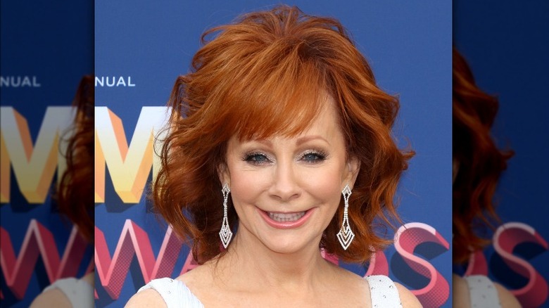 Reba McEntire souriante, portant de grosses boucles d'oreilles