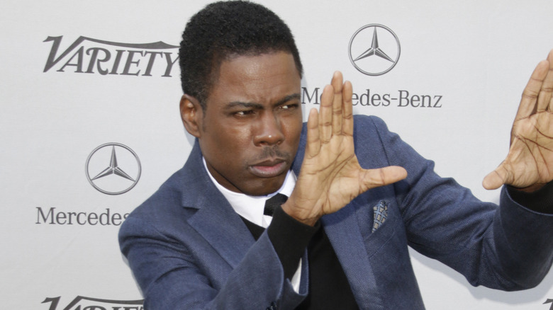 Chris Rock posant avec les mains en l'air