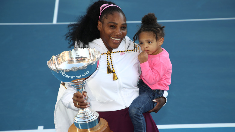 Serena Williams tenant sa fille et un trophée