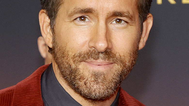 Ryan Reynolds portant une veste rouge, souriant