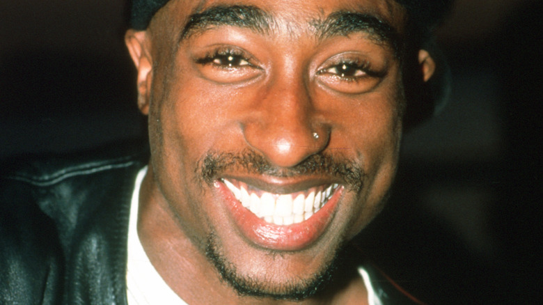 Tupac Shakur sourit en portant une casquette noire.