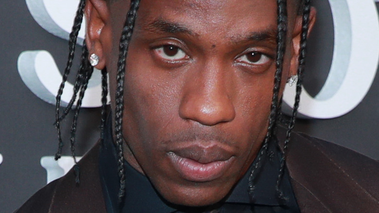 Travis Scott tête baissée regardant dans la caméra