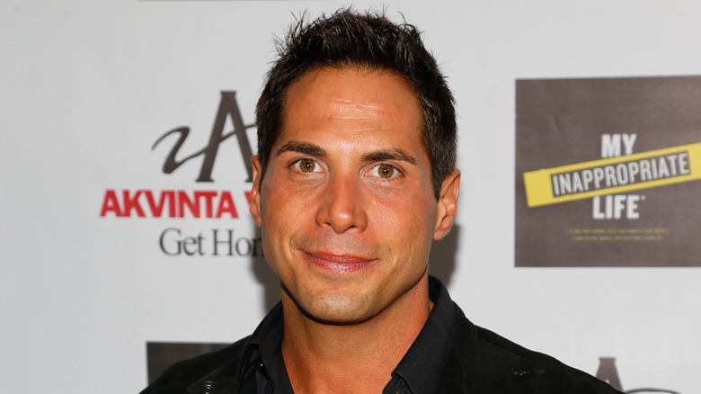 Joe Francis debout devant un step-and-repeat