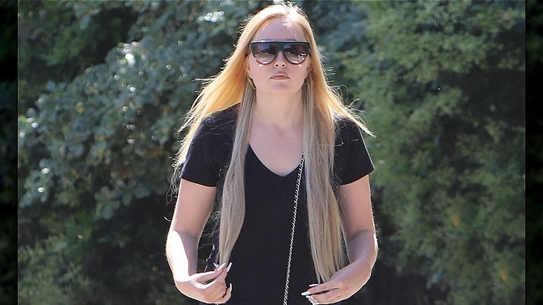 Amanda Bynes avec de longs cheveux blonds et des lunettes de soleil, marchant