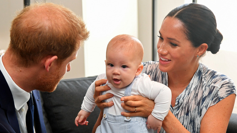 Meghan Markle tenant son fils, Archie, avec le prince Harry le regardant.