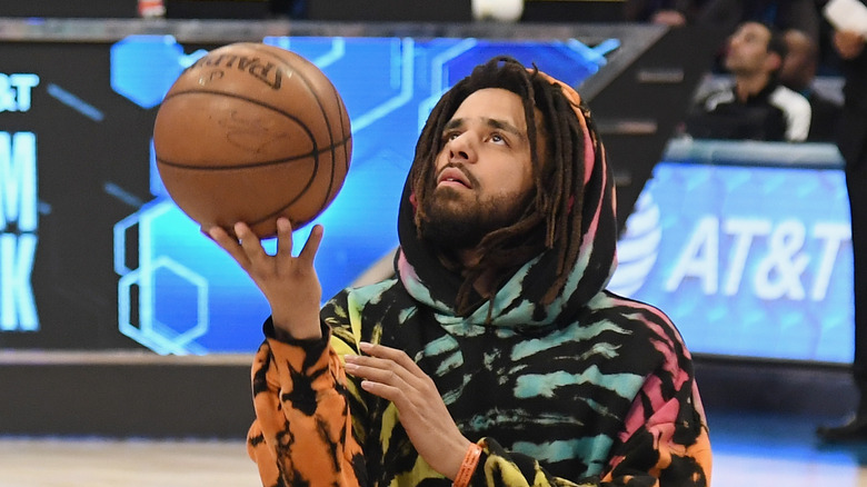 J. Cole tenant un ballon de basket