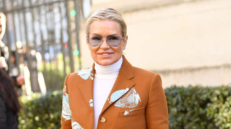 Yolanda Hadid souriant devant un buisson