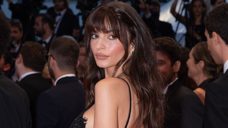 Emily Ratajkowski regarde par-dessus son épaule