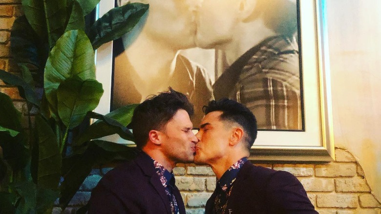 Tom Schwartz embrassant Tom Sandoval sous une photo d'eux s'embrassant