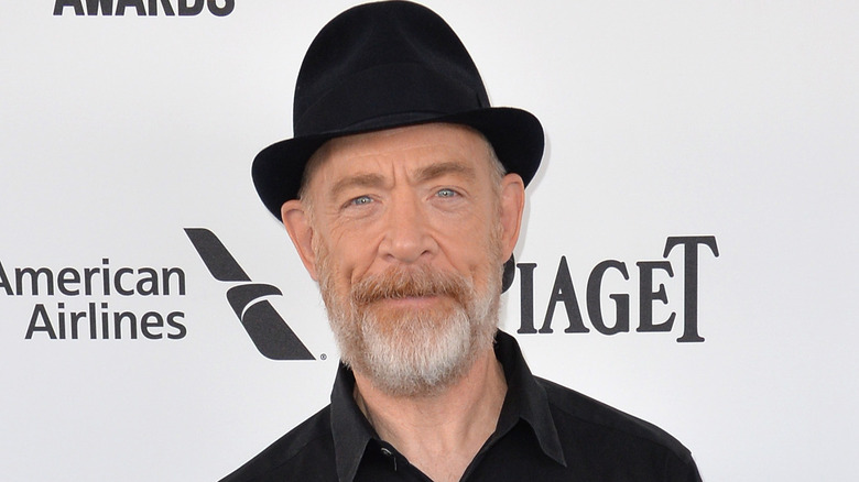 JK Simmons souriant avec un chapeau noir