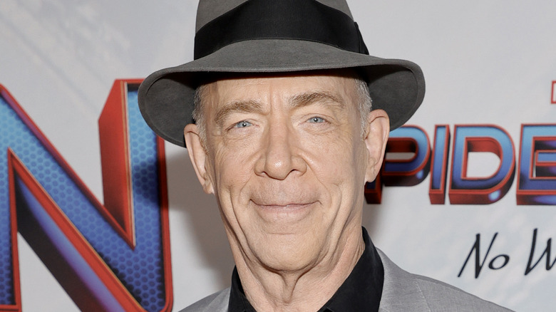 JK Simmons souriant dans un chapeau gris