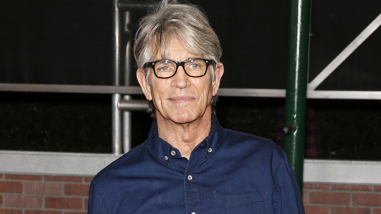 Eric Roberts pose avec des lunettes à monture noire et une chemise en jean