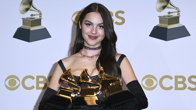 Olivia Rodrigo souriante et tenant trois Grammys