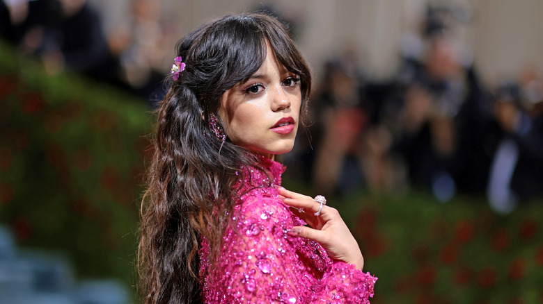 Jenna Ortega pose en regardant par-dessus son épaule dans une tenue entièrement rose