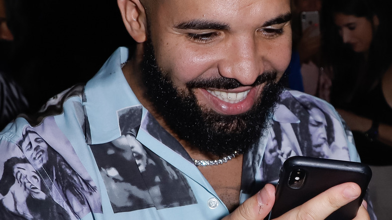 Drake souriant à son téléphone