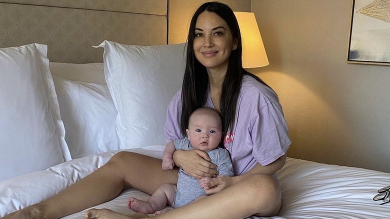 Olivia Munn, tenant bébé Malcolm sur son lit