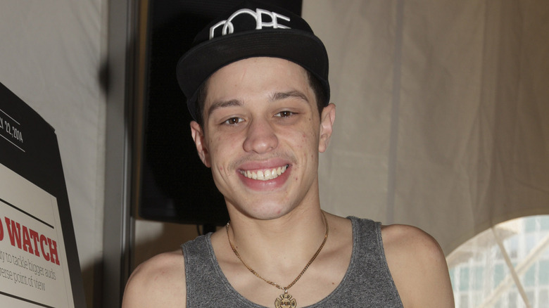 Pete Davidson portant un débardeur et un chapeau noir