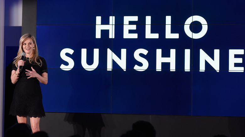 Reese Witherspoon s'exprimant à côté du logo Hello Sunshine