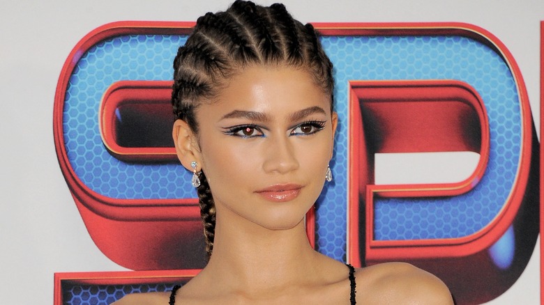 Zendaya portant des boucles d'oreilles pendantes, posant