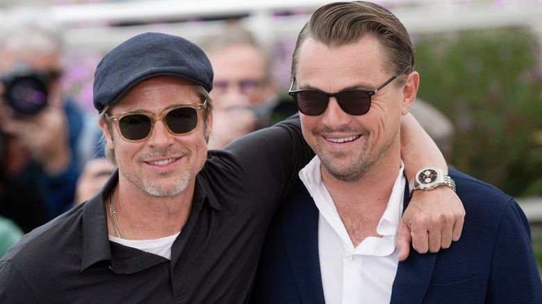 Brad Pitt souriant avec un bras autour de Leonardo DiCaprio