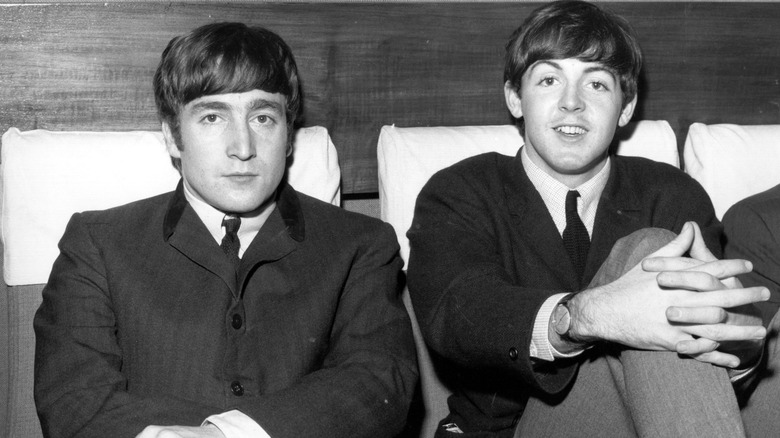 John Lennon et Paul McCartney sont allongés dans des sièges sur une photographie en noir et blanc des années 1960