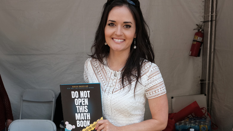 Danica McKellar souriante en tenant son livre, "N