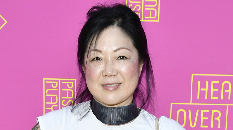 Margaret Cho souriant devant un fond rose