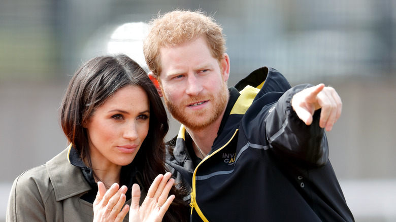 Le prince Harry montre du doigt pendant que Meghan Markle regarde