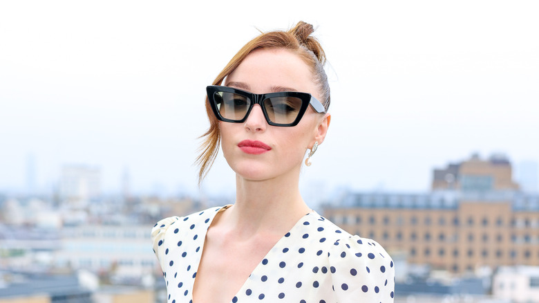 Phoebe Dynevor sur un balcon avec des lunettes de soleil