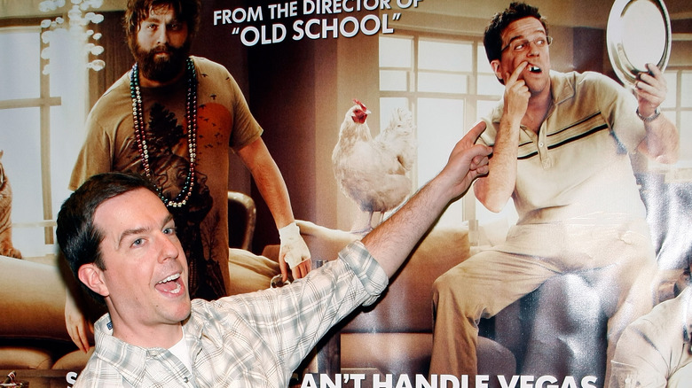 Ed Helms montrant l'affiche Hangover