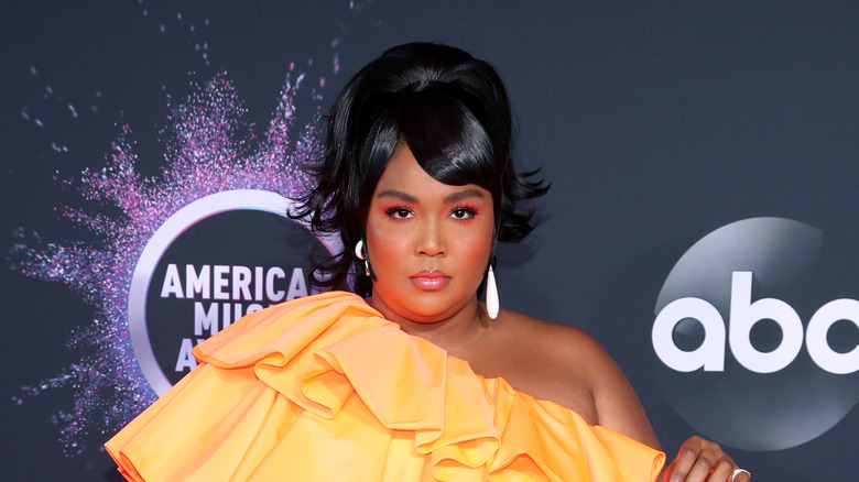 Lizzo en robe orange, posant