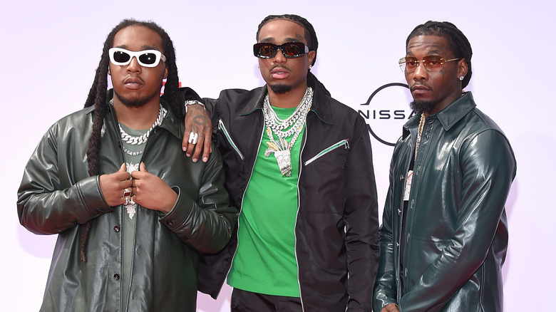 Migos en vestes noires, posant