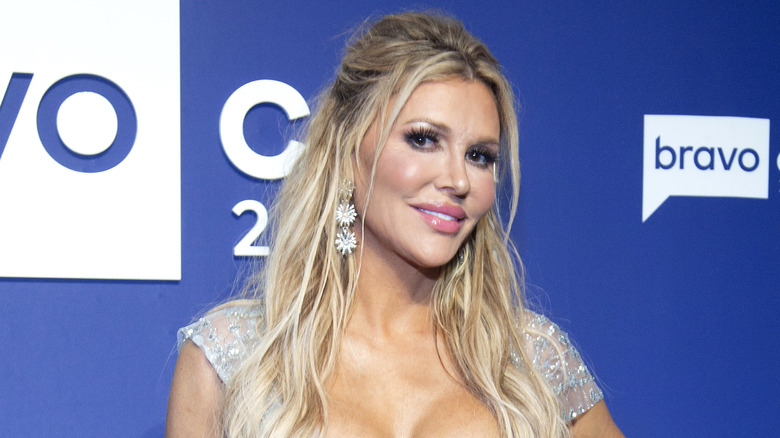 Brandi Glanville souriante, boucles d'oreilles fleurs