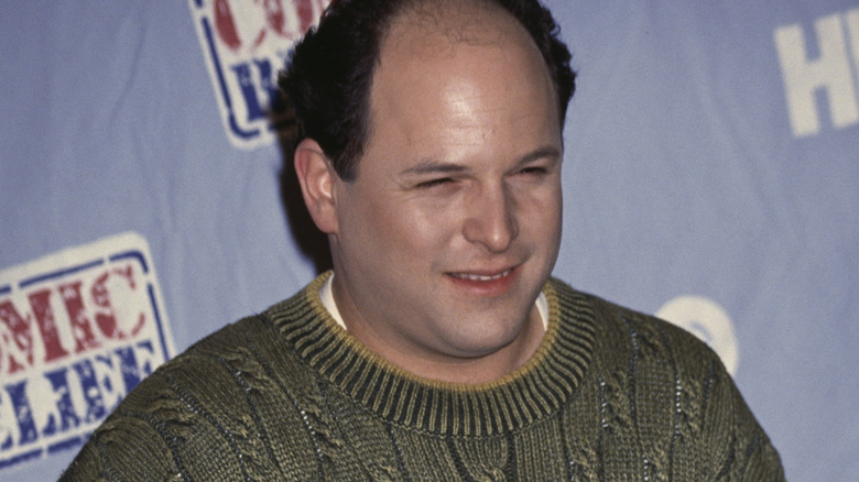 Jason Alexander souriant, pull tricoté