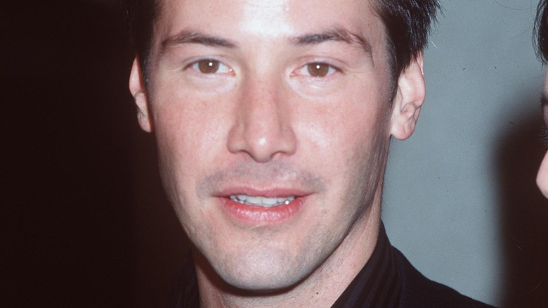 Keanu Reeves aux cheveux courts, posant