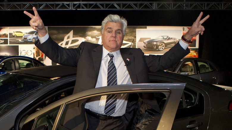 Jay Leno donnant des signes de paix près d'une voiture