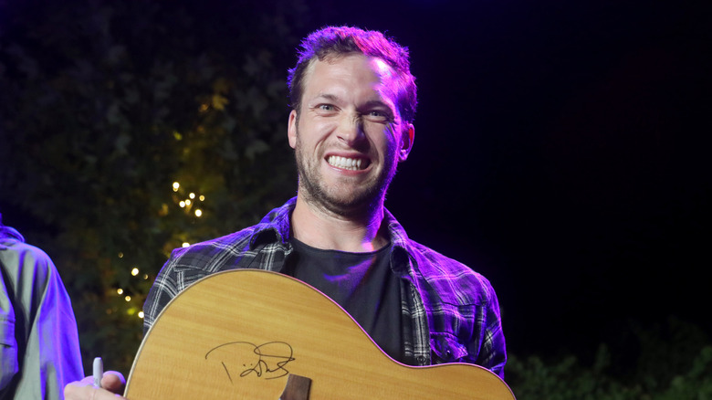 Phillip Phillips souriant avec une guitare