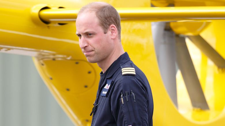 Prince William debout à côté d'un hélicoptère