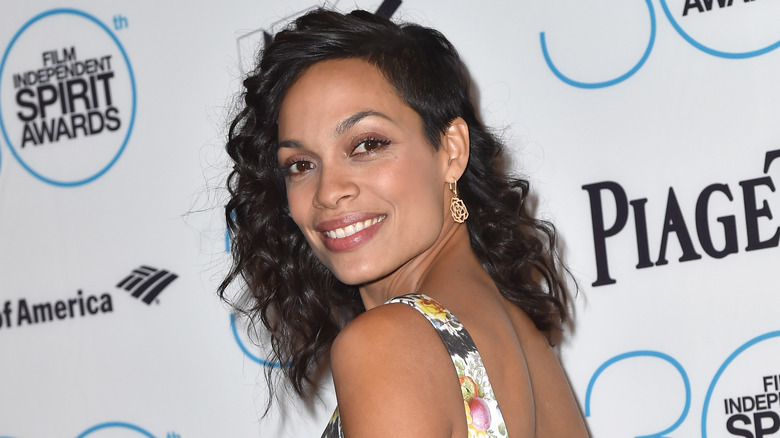 Rosario Dawson souriant par-dessus son épaule