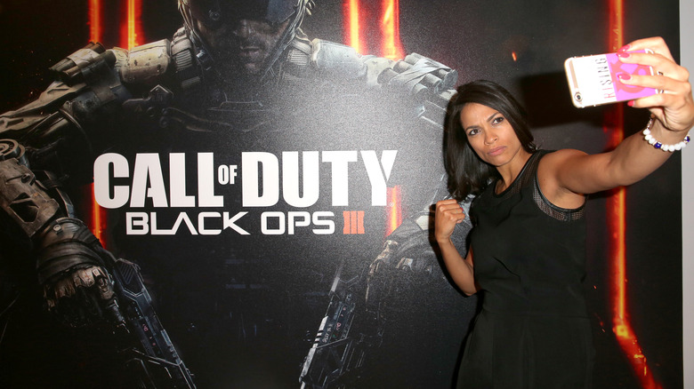 Rosario Dawson posant à côté de l'affiche promotionnelle de COD