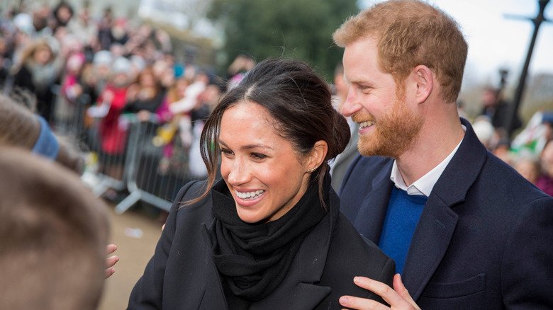 Meghan et Harry rient en saluant les fans royaux