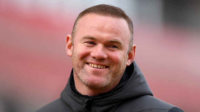 Wayne Rooney portant une veste en souriant 